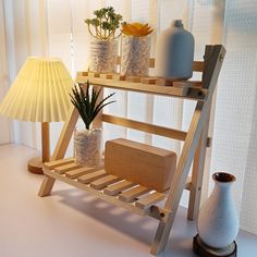 a wooden shelf with vases on it and a lamp next to it in front of a window