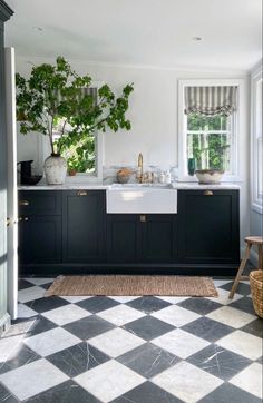 a black and white checkered floor in a kitchen with potted plants on the counter