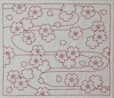 a white table cloth with red stitching and flowers on the border, in front of a