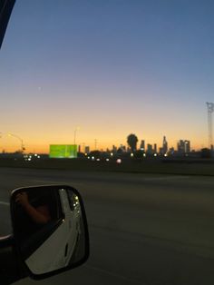 a view of the city from inside a car window at sunset or dawn with buildings in the distance