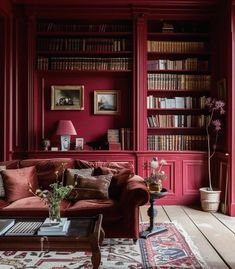 a living room filled with lots of red furniture and bookshelves full of books