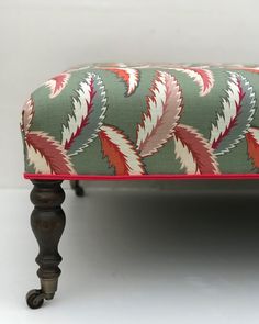 an upholstered bench with red and green leaves on it