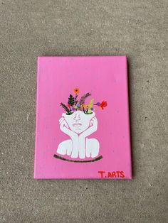 a pink square with a painting of a woman holding flowers in her hand on the ground