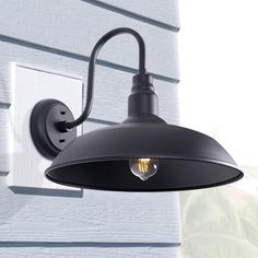 a black outdoor light on the side of a house next to a white wall and window