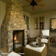 a living room filled with furniture and a fire place next to a stone covered fireplace