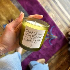 a person holding a candle in their hand with the words smells like you're getting married on it