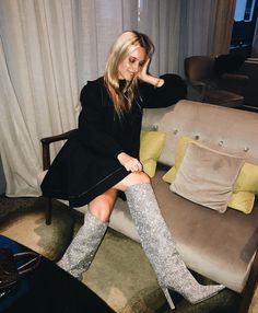 a woman sitting on top of a couch next to a chair