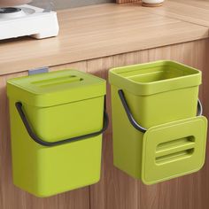 two lime green trash cans hanging on the side of a kitchen counter next to a toaster