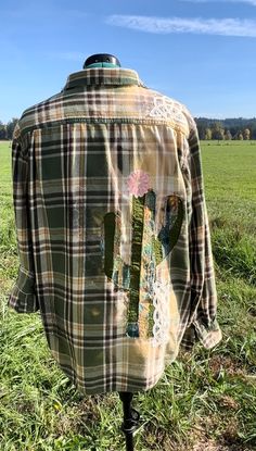 a plaid shirt with cactus patches on the front and back, sitting in a grassy field