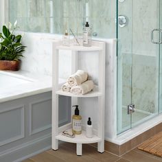 a corner shelf in the bathroom with towels and soaps on it next to a bathtub