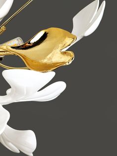 a gold and white bird ornament hanging from a ceiling fixture with leaves on it