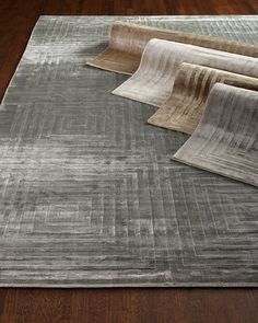 an area rug with different shades of gray and white on top of wood flooring