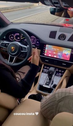 a woman driving a car with her hands on the steering wheel, while looking at an electronic screen