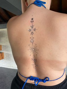 a woman with a tattoo on her back is looking at the camera while wearing blue string