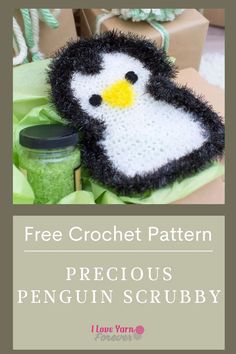 a penguin made out of yarn sitting on top of a green bag with the text free crochet pattern precious penguin scrubby