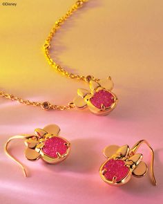 two gold necklaces with pink stones in the shape of flowers on a yellow background