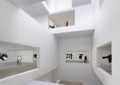 two people are standing in an art gallery looking at artwork on the walls and floor