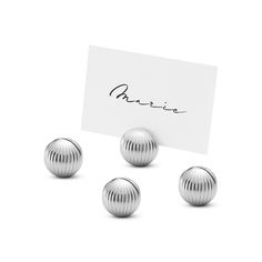 three silver balls sitting next to a white card