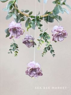 purple flowers hanging from a branch with green leaves