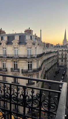 a balcony with black iron railings and buildings in the background at sunset or dawn