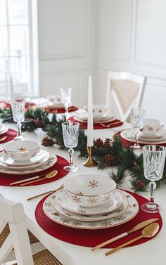 the table is set for christmas dinner with red and gold place settings