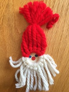 a red and white knitted santa hat on top of a wooden table