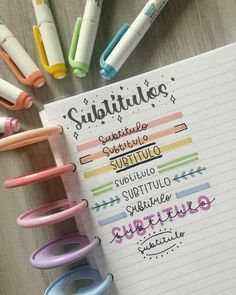 some pens are sitting on top of a notebook with writing in different colors and sizes