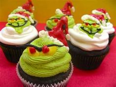 some cupcakes with green frosting and decorations on them are sitting on a table