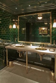 a green tiled bathroom with two sinks and mirrors