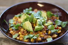 a bowl filled with corn, black beans and avocado garnished with cilantro