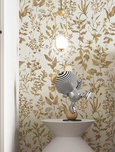 a white vase sitting on top of a table in front of a wallpapered wall