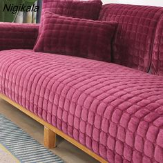 a fuchsia colored couch with two pillows on it and a plant in the background