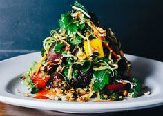 a white plate topped with a salad covered in lots of veggies and nuts