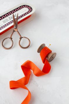 an orange ribbon and some scissors on a table