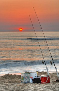 two fishing rods are on the beach at sunset