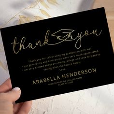 a person holding up a black and gold thank card with the words, thank you