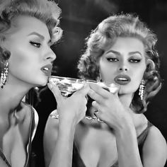 two women are drinking martinis in black and white