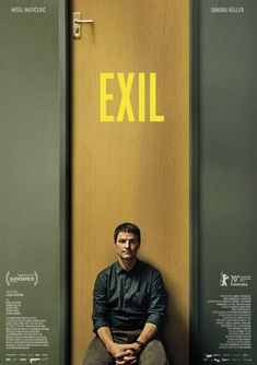 a man sitting on the floor in front of a wooden door that says exile