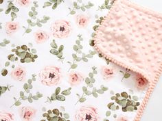 a close up of a blanket with flowers on it and a pink dotty bib