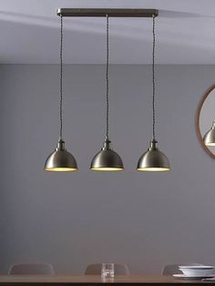 three pendant lights hanging over a dining room table