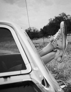 a woman sitting in the back seat of a car with her legs hanging out the window