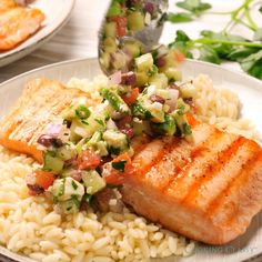 salmon and rice with cucumber garnish on a white plate, ready to be eaten