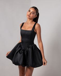 Introducing the Black Corset Sheen Mini Bubble Dress, a statement piece that exudes bold elegance and modern glamour. Crafted from our luxurious, runway-inspired sheen fabric, this dress catches the light beautifully, giving it a rich, polished look. The structured corset bodice cinches the waist to create an alluring hourglass silhouette, while offering impeccable support and comfort. The dramatic bubble skirt adds volume and a playful touch, making this mini dress a true standout. Perfect for special occasions, this dress promises to captivate and leave an unforgettable impression, blending timeless style with a modern edge. Black Dress With Bow In The Back, Black Corset Dress Short, Bubble Skirt Dress, Corset Black Dress, Corset Dress Outfit, Corset Dress Formal, Corset Dress Short, Corset Dress Black, Short Corset Dress