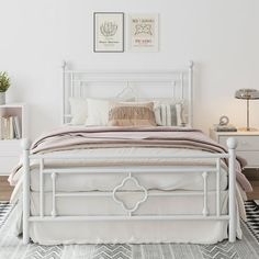 a white bed sitting on top of a wooden floor next to a nightstand and lamp