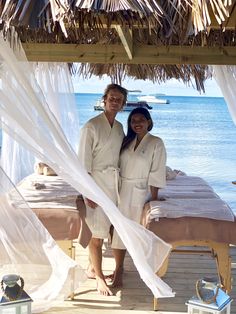 two people standing in front of a bed on the beach