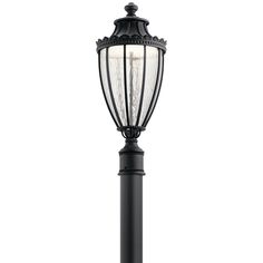 an outdoor lamp post with a white light on the top and black metal posts around it