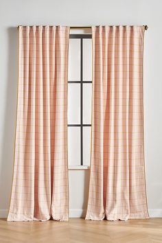 the curtains are hanging on the window sill in front of an empty room with hardwood floors