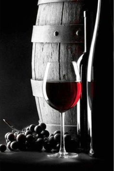 a glass of wine next to a barrel and some grapes