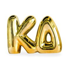 the letter k is made out of gold foil and sits in front of a white background