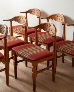 a set of six chairs with red upholstered seats and striped seat covers on them